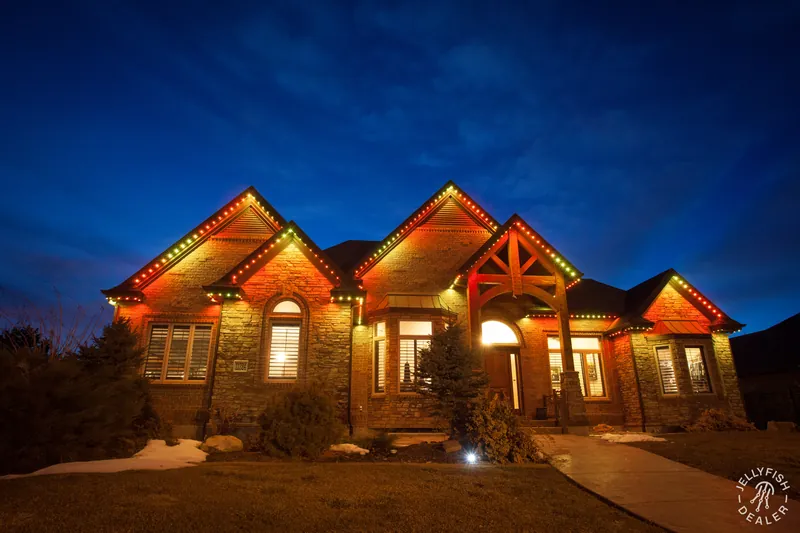 Orange and green fall permanent holiday lighting on a brick home