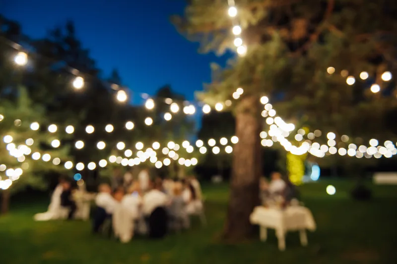 Cafe-style bistro string lights glowing over an outdoor evening gathering